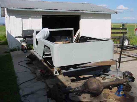 1976 Jeep CJ7 - A disassembled Jeep CJ body sits on stands next to a detached rear axle.