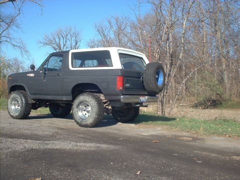 1986 Ford Bronco - Modified Ford Bronco from the 1980s, seen from the rear with a spare tire and lifted suspension.