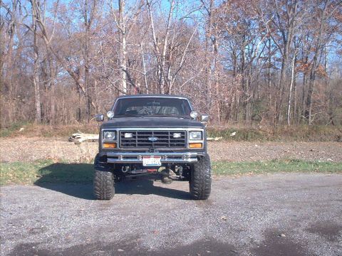 1986 Ford Bronco - This lifted 1980s Ford Bronco is presented from a front-facing perspective, its substantial tires and build.