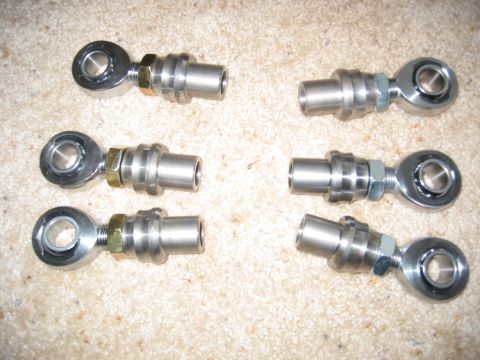 1991 Ford Explorer - Six rod ends with adapters are laid out on a carpeted surface, likely for a vehicle modification.