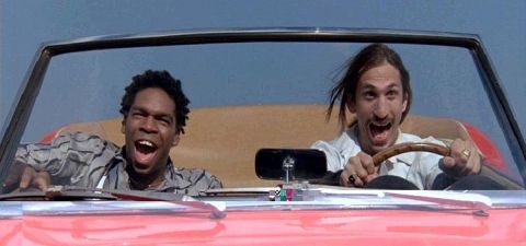 1996 Ford Probe - Two men joyfully ride in a red convertible under a clear blue sky.