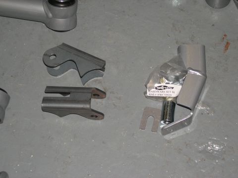 2001 Jeep Wrangler - Several metal suspension components and a hardware kit are displayed on a concrete surface.