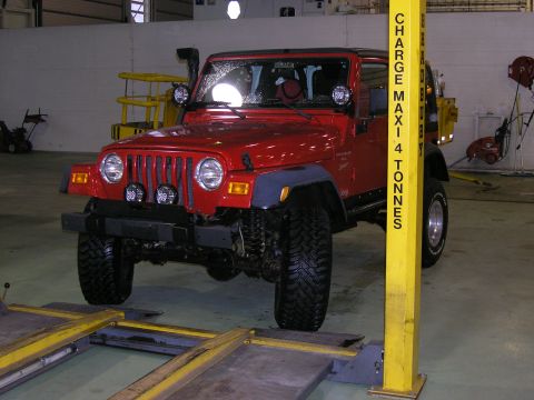 2001 Jeep Wrangler - A red Jeep Wrangler TJ is shown in a garage, equipped with a snorkel and auxiliary lights.