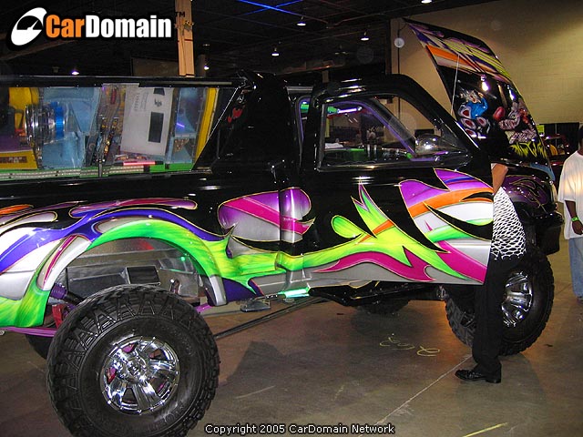 Black pickup truck with wild purple, green, and orange graphics. Hood is open showing more custom paint