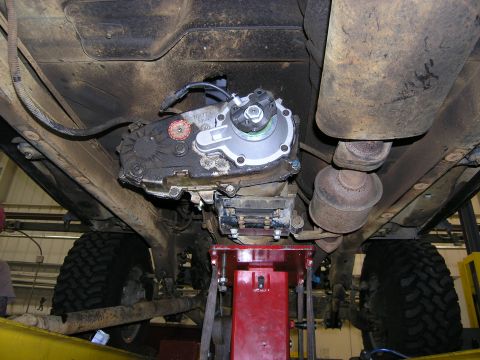 2001 Jeep Wrangler - The underside of a vehicle shows the transfer case and exhaust system, elevated on a red lift for service.