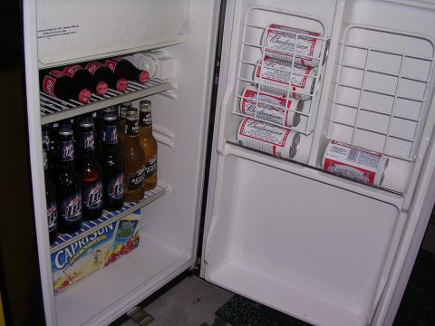 1985 Ford Bronco - Interior of an open refrigerator filled with various canned and bottled beverages.