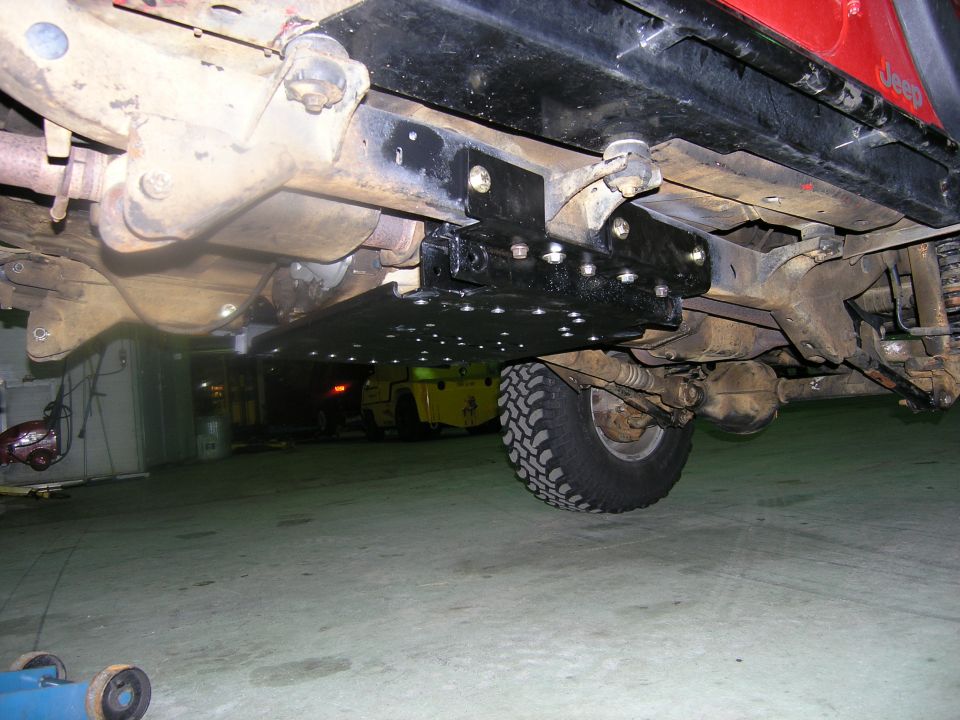Red Jeep TJ underbody with skid plate and suspension components visible