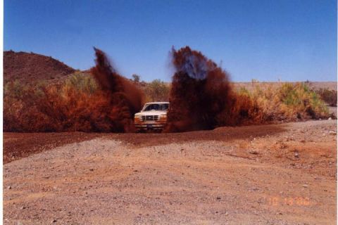 1993 Ford Bronco - A white 1992 Ford Bronco navigates a muddy trail, sending dirt and water flying.