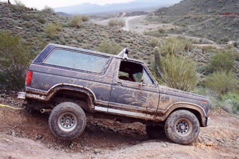 1993 Ford Bronco - This SUV navigates a challenging off-road terrain, covered in mud from its adventure.