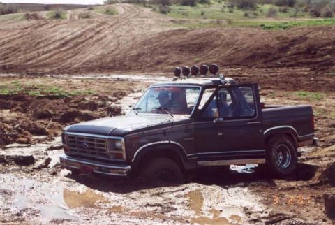 1993 Ford Bronco - This Ford Bronco appears to be from the early 1980s and is deeply mired in a muddy off-road area.
