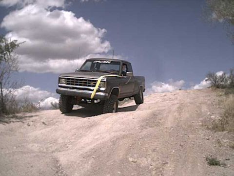1993 Ford Bronco - A Ford Ranger pickup truck navigates a dusty, off-road trail under a cloudy sky.