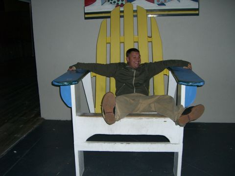1996 Ford Probe - Man sits in a giant Adirondack chair, looking excited.