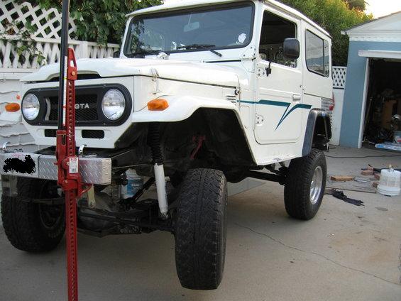 White 1977 Toyota Land Cruiser with a red Hi-Lift jack mounted on the front bumper