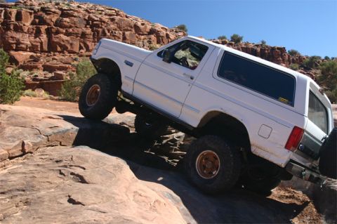 1993 Ford Bronco - White 1993 Ford Bronco navigating a rocky trail with a clear blue sky overhead.