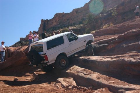 1993 Ford Bronco - A white 1992 Ford Bronco navigates a challenging rocky trail under a clear blue sky.