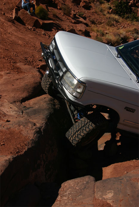 1993 Ford Bronco - This SUV is tackling a challenging off-road path with steep inclines and large rocks.