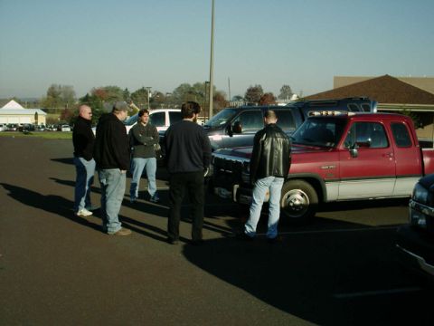 2002 Ford F-250 - A group of men stand around a red and white Dodge Ram pickup truck in a parking lot.