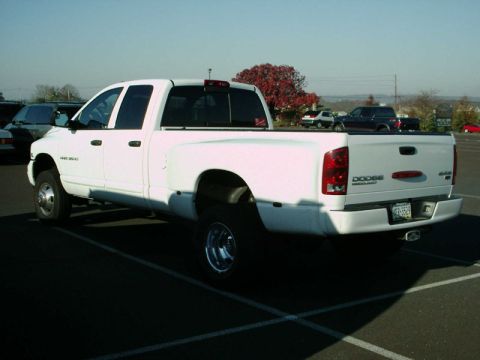 2002 Ford F-250 - This white Dodge Ram 3500 pickup truck is parked in a lot on a sunny day.