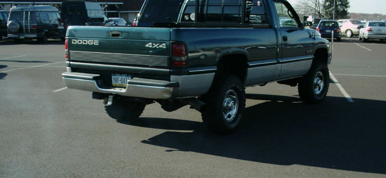 Lifted green and silver Dodge Ram 4x4 regular cab pickup, rear three-quarter view on mud tires
