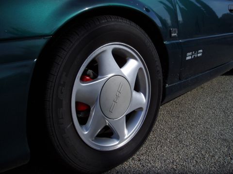 1993 Ford Taurus - Close-up of a green 1993 Ford Taurus showing the wheel, fender, and side body panel.