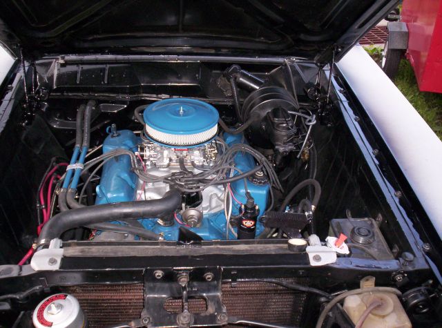 Engine bay with blue V8 engine and chrome round air cleaner in a black vehicle