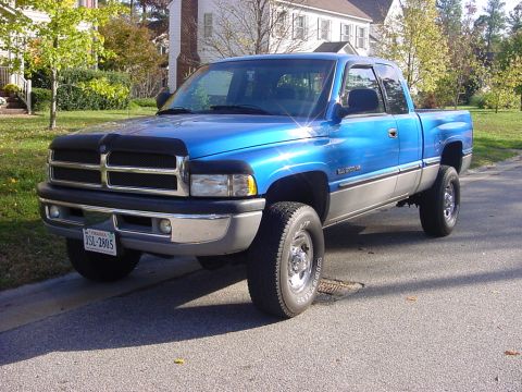 1989 Ford Bronco - A blue and silver Dodge Ram pickup truck is parked on a residential street.