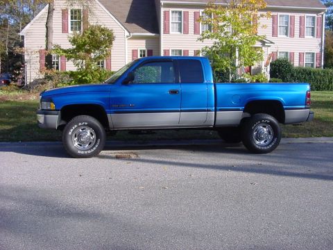 1989 Ford Bronco - This blue and silver pickup truck is shown from the side. The text on the tire reads "BAJA A/T".