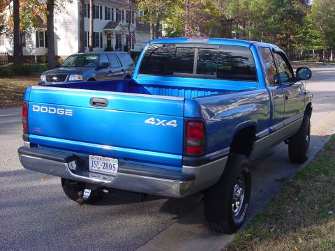 1989 Ford Bronco - A blue Dodge pickup truck is parked on a street, with another SUV visible in the background.