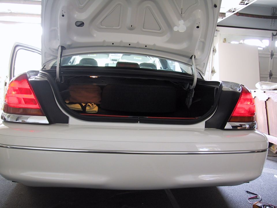 White 2003 Ford Crown Victoria rear with open trunk showing spare tire and luggage