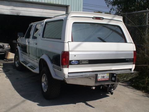 1993 Ford C-350 (Centurion Conversions) - This white Ford SUV features a distinctive green stripe and an aftermarket rear bumper. The license plate reads P B4WEGO.