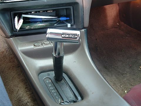 1994 Ford Thunderbird - The interior of a car shows an aftermarket automatic gear shifter with "Tractives" branding and a coin holder.