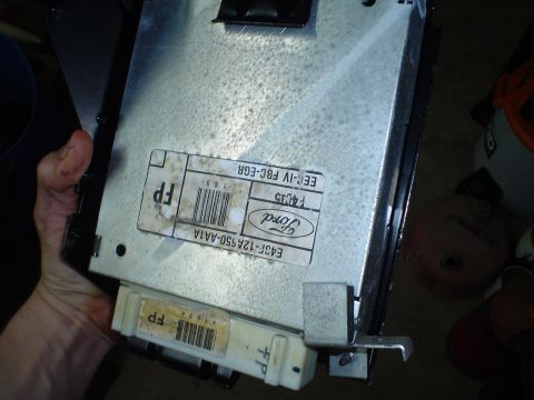 1984 Ford Bronco - A hand holds a Ford electronic control unit, showing various labels and connectors.