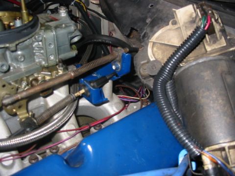 1985 Ford Crown Victoria LTD - Close-up view of a vehicle's engine bay, showing the carburetor, blue valve cover, and various wires and hoses.