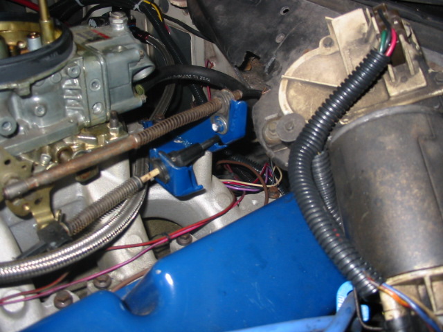 Engine bay with carburetor, blue valve cover, and wiring