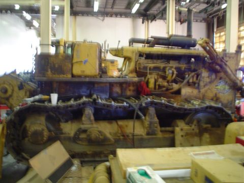 1966 International School Bus - Crawler tractor engine and tracks visible in a workshop setting.