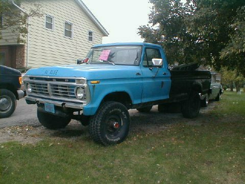 1986 Ford Bronco - A blue 1973 Ford F-Series pickup truck is parked in front of a house, with another vehicle visible behind it.