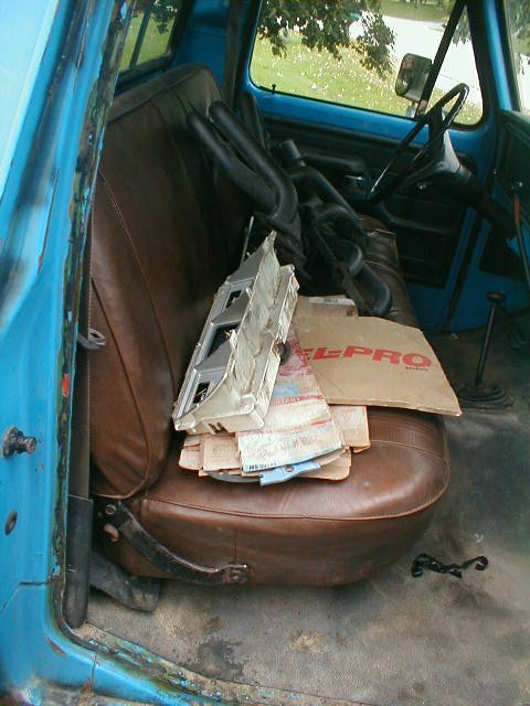 1986 Ford Bronco - The interior of a blue truck shows brown seats piled with parts and a steering wheel visible.