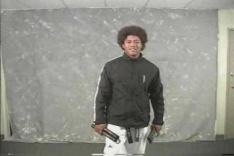 1991 Ford Bronco - A man with an afro stands holding nunchucks in front of a grey backdrop.