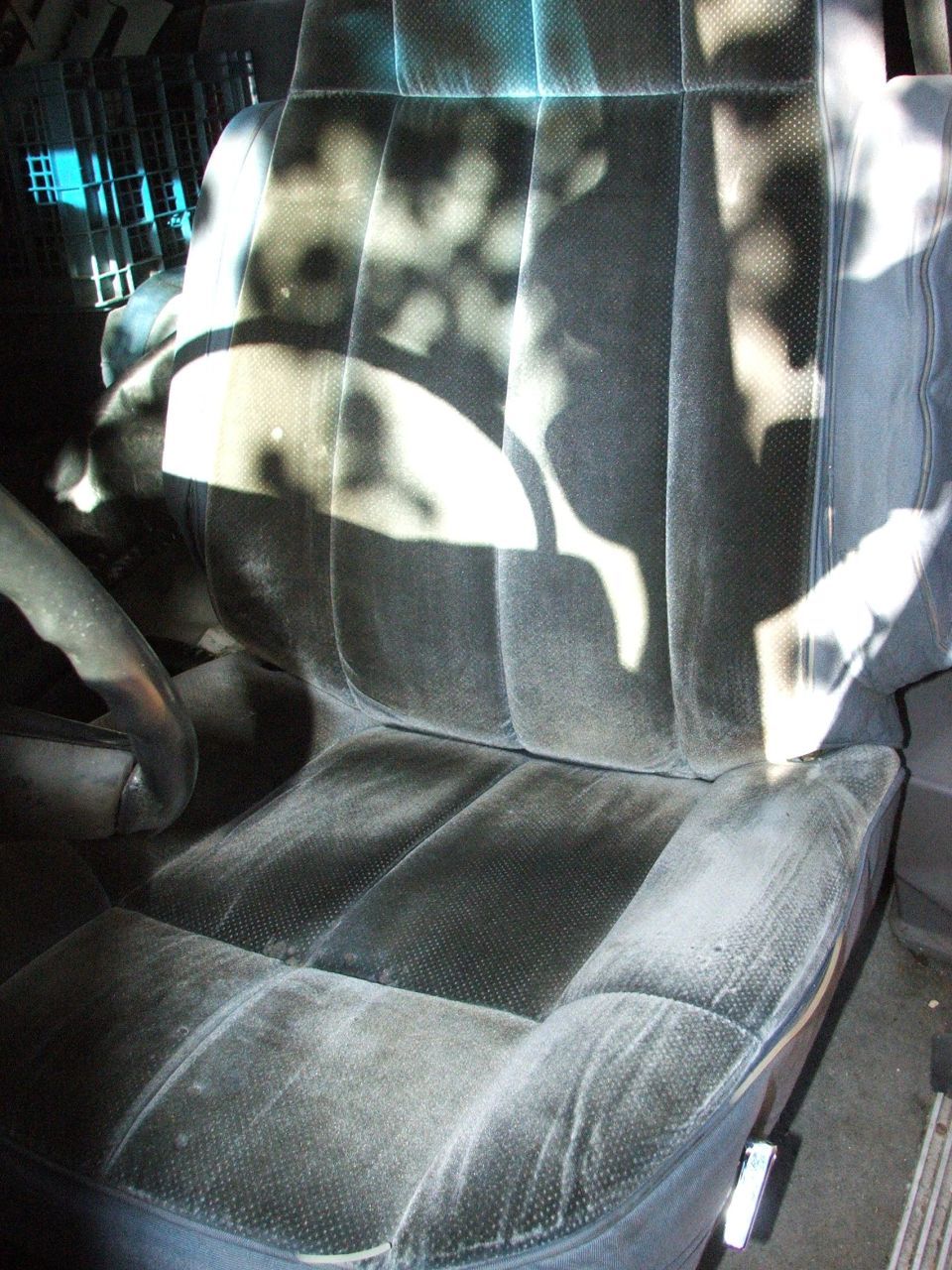 Worn gray velour front bucket seat inside a truck cab, sunlight dappled