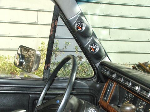 1996 Ford Bronco - Interior view shows aftermarket gauges and a worn dashboard, with a reflection in the side mirror.