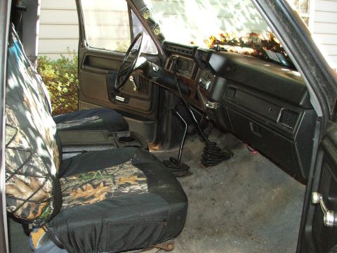 1996 Ford Bronco - The interior of a truck is shown, camouflage seat covers and a manual shifter.