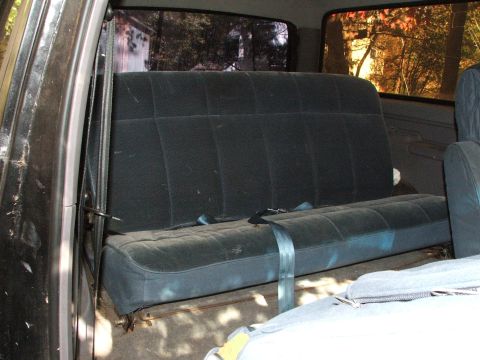 1996 Ford Bronco - Rear bench seat interior of a vehicle, showing seatbelts and dark fabric upholstery.