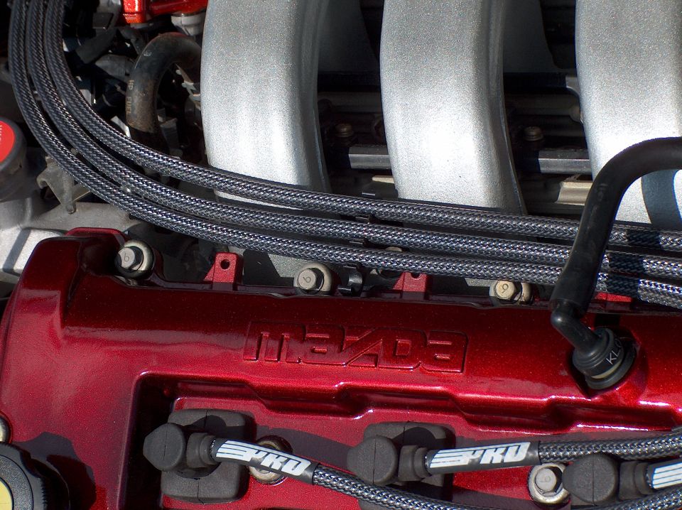 Candy red Mazda valve cover with braided spark plug wires under an aluminum intake manifold