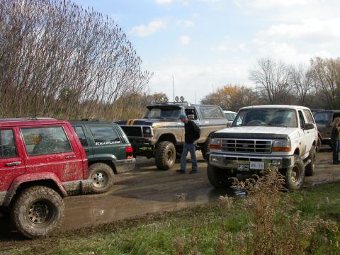 1996 Ford Bronco parked in mud next to other off-road vehicles