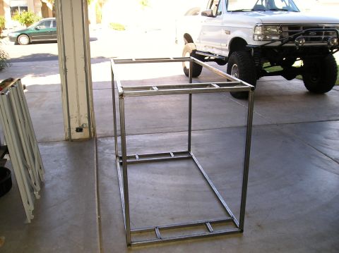 1993 Ford Bronco - A white 1993 Ford Bronco is parked in a driveway next to a metal frame structure.