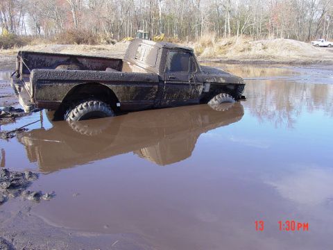 1995 Dodge 1500 - A heavily mud-caked pickup truck is stuck in a muddy pool, with only its upper body visible.