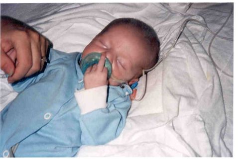 1989 Ford Bronco - A newborn baby rests with a pacifier and medical tubing attached.