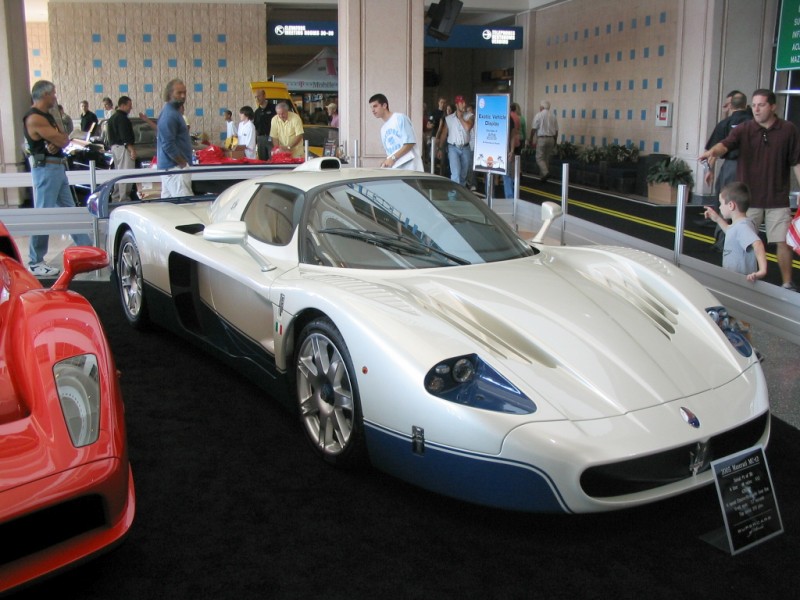 White and blue sports car with a red car to its left