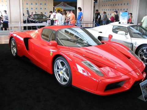 1997 Ford Probe - A red Ferrari sports car is displayed indoors with other vehicles and people in the background.