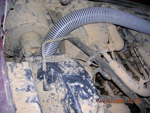 1989 Ford Bronco II - This image shows a close-up view of engine components, including hoses and a power distribution box, covered in dirt.